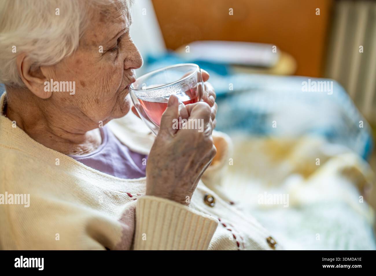 Donna anziana che beve una tazza di tè in una casa di cura Foto Stock