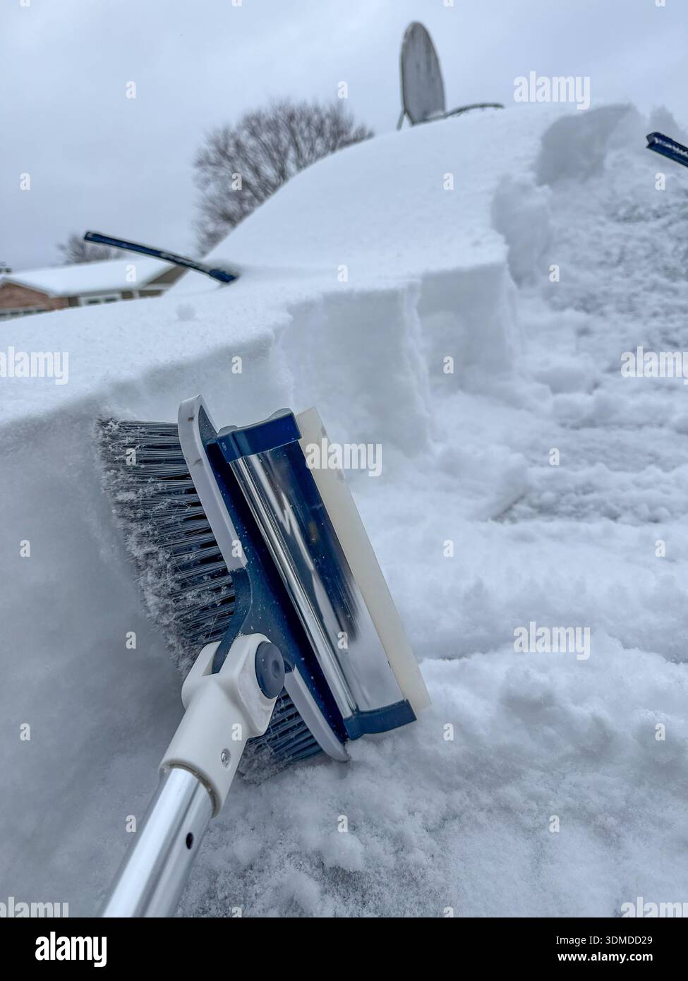 Una spazzola per raschietto utilizzata per eliminare la neve da un veicolo in una giornata invernale buia e grigia Foto Stock