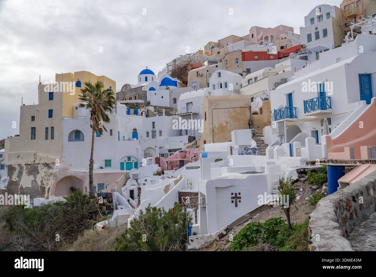 Oia (Apano Meria o Pano Meria), Santorini, Grecia. Architettura classica delle Cicladi caratterizzata da edifici imbiancati e chiese dalla cupola blu che si arrampicano Foto Stock