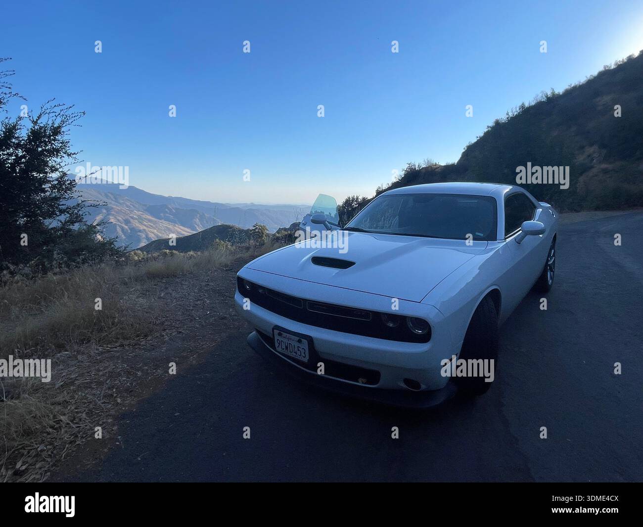 White Muscle car parcheggiata su una strada panoramica di montagna che si affaccia sulla valle in California, Stati Uniti. - Immagine stock catturata con smartphone