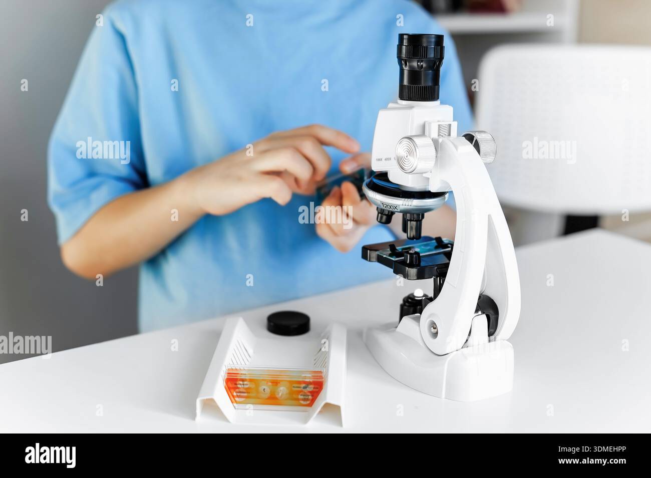 Bambino che usa un microscopio per imparare la scienza a casa o a scuola. Concetto di formazione precoce con esperimenti pratici, curiosità, apprendimento STEM e modernità Foto Stock