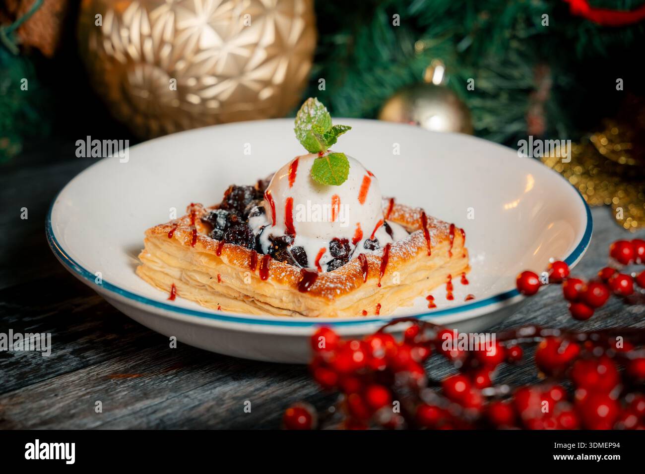 Un dessert con una foglia verde sopra e una paletta di gelato. Il dessert è servito in una ciotola bianca Foto Stock