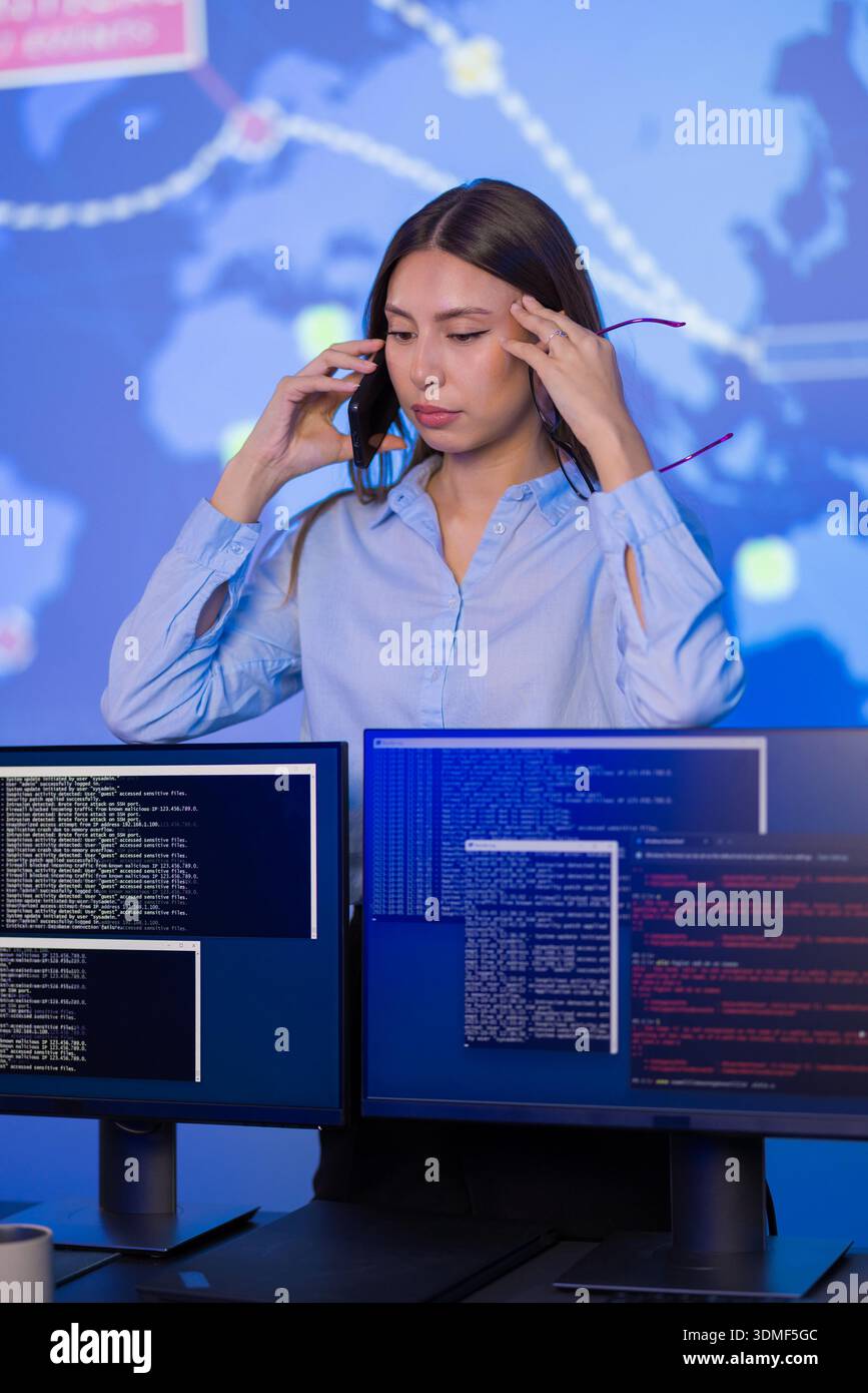 Analista donna che monitora le minacce alla sicurezza informatica in una sala di controllo Foto Stock