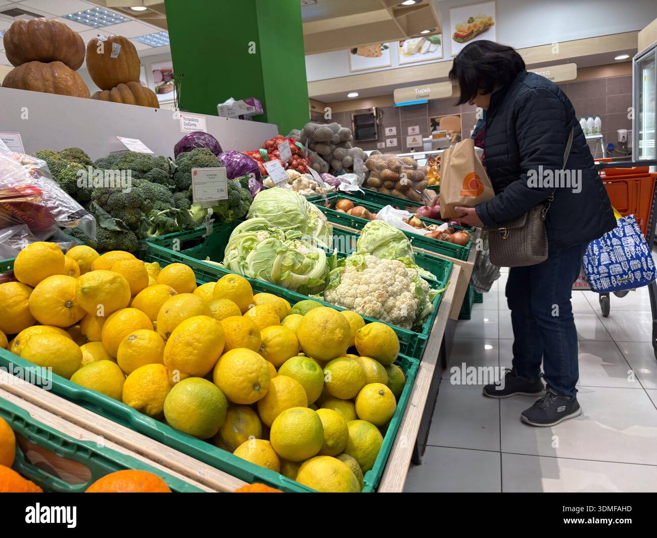 Donna che acquista verdure fresche come limoni, broccoli e cavolfiore in una sezione di prodotti del supermercato greco. Consumismo, vendita al dettaglio. Foto Stock