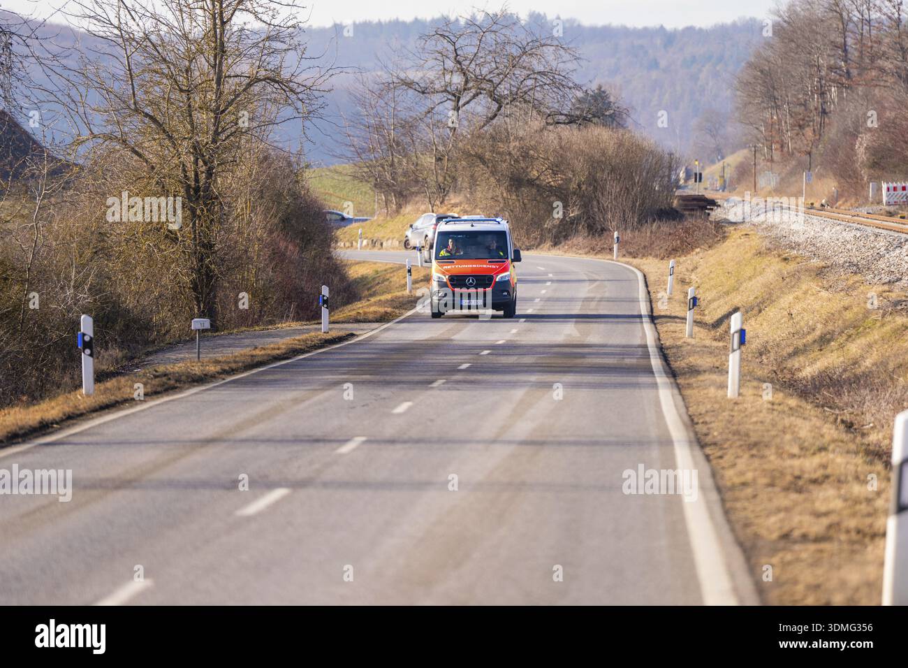 Un'ambulanza sta guidando su una strada rurale. Vegetazione sparsa e alberi circondano la strada, esercitazioni dei vigili del fuoco sulla ferrovia Hermann Hesse, Ostelsh Foto Stock