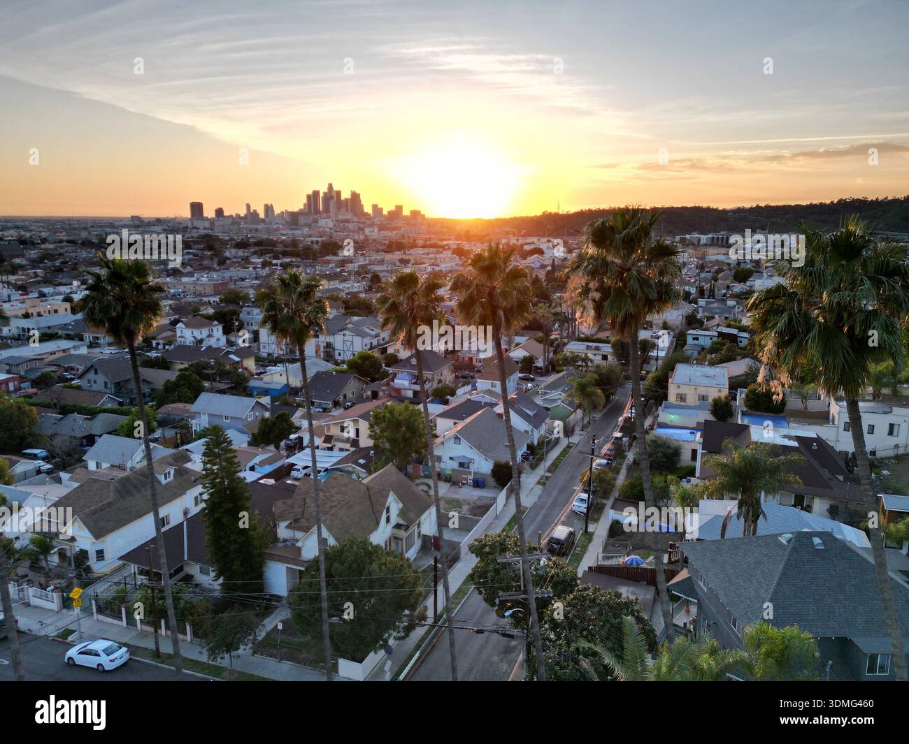 Tramonto dorato con palme classiche in vista in primo piano dello skyline del centro di Los Angeles in lontananza all'orizzonte Foto Stock