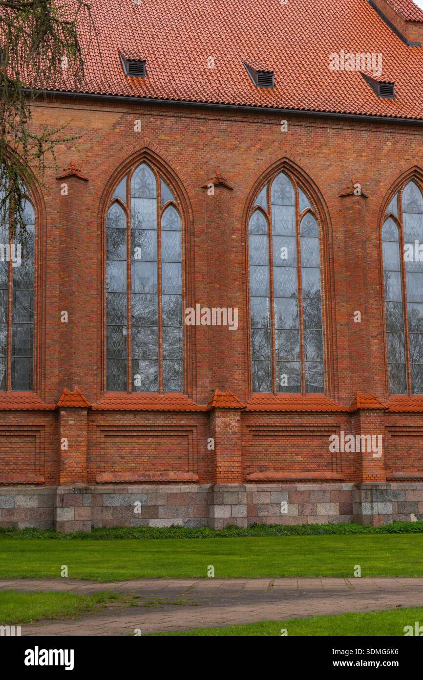 Le pareti della chiesa in stile gotico a Druskininkai, Lituania, mostrano finestre ad arco a punta, vetro con piombo, tetto in piastrelle di argilla, fondazioni in granito e alberi senza fronzoli Foto Stock