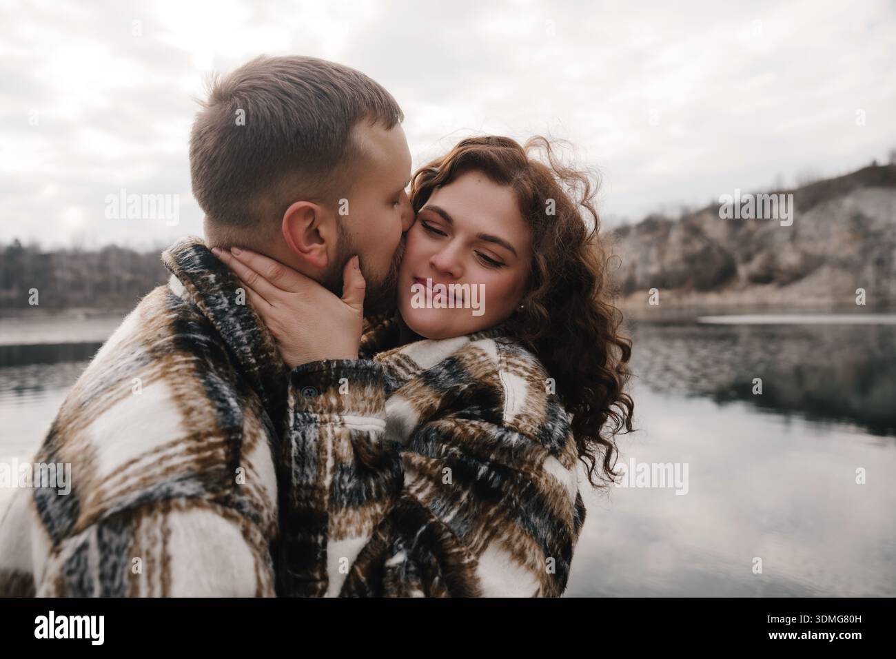 Due persone mostrano il loro amore l'uno per l'altro vicino all'acqua il giorno di San Valentino, godendosi un momento speciale insieme nella natura. Foto Stock