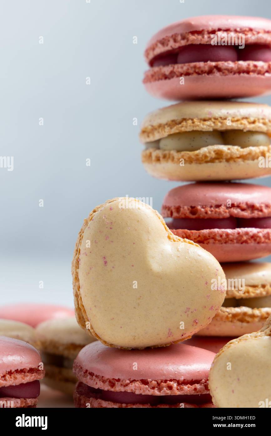 Un'esposizione di macaron è disposta in una pila ordinata con vari colori come il rosa e il beige. Foto Stock