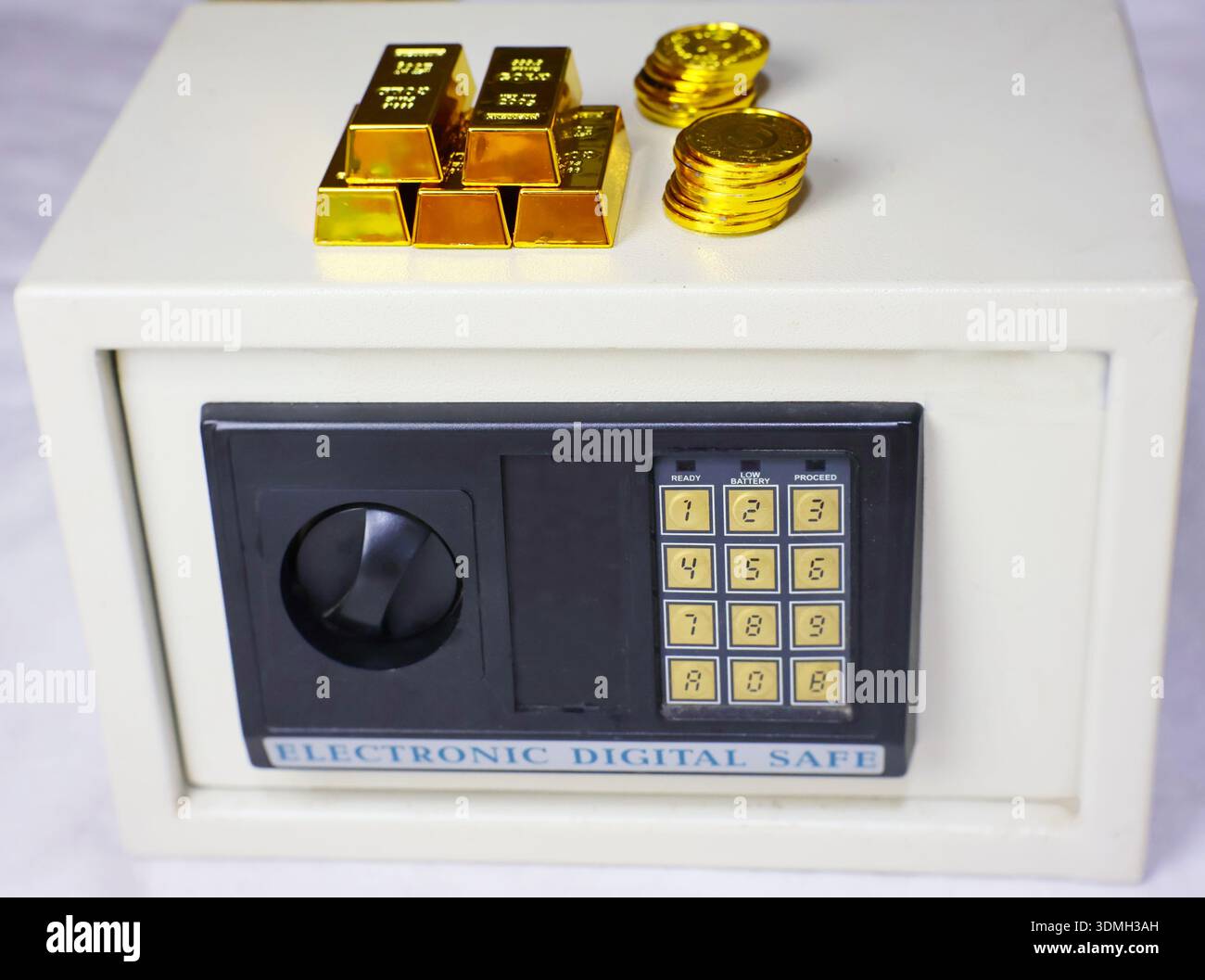Una cassaforte digitale in miniatura con lingotti d'oro e monete d'oro in cima simboleggia la ricchezza, gli investimenti e la sicurezza dei beni personali. Foto Stock
