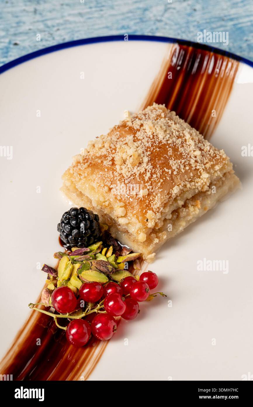 Presentazione moderna del dessert baklava con guarnizione di pistacchio e frutti di bosco Foto Stock