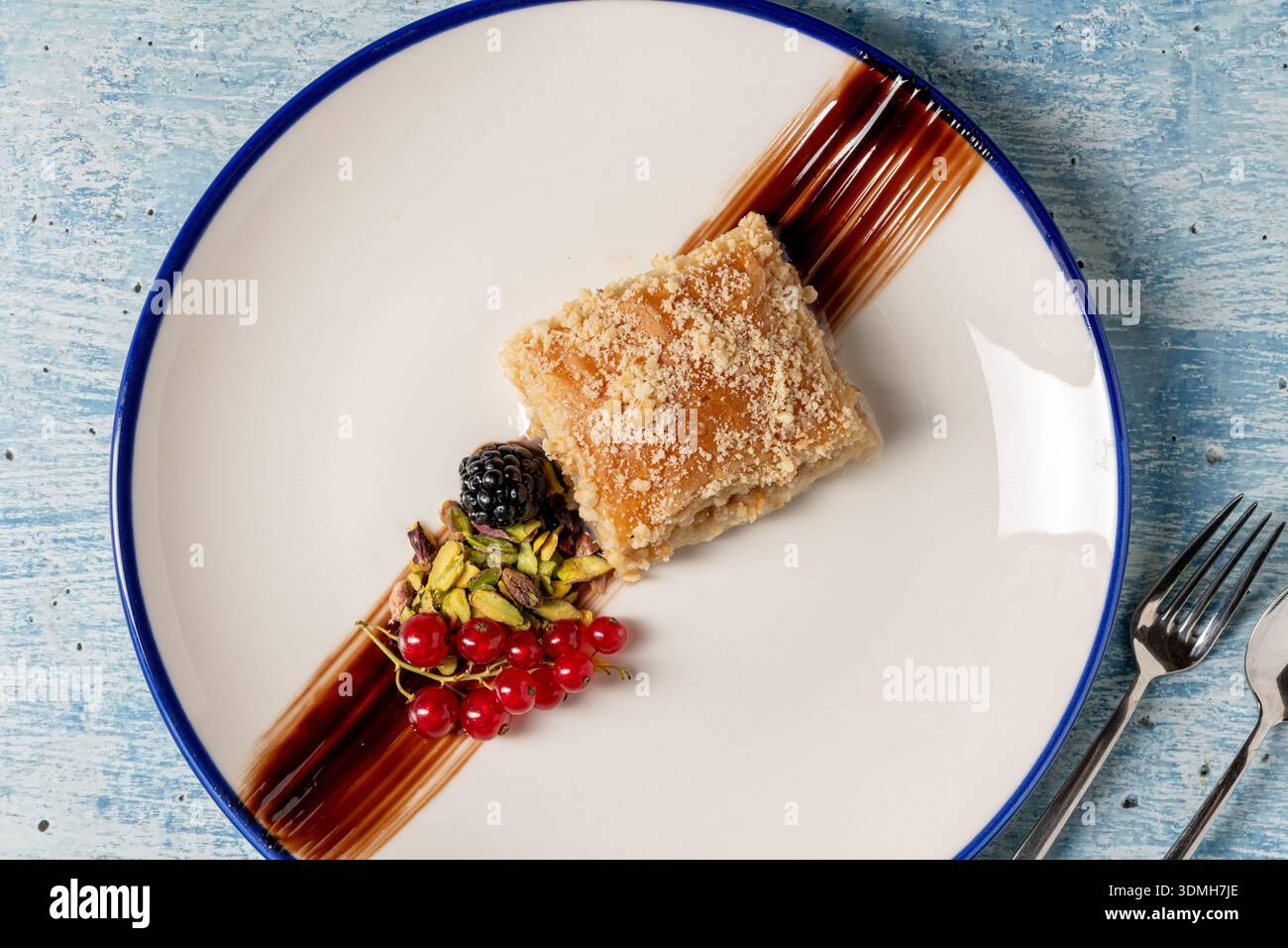 Presentazione moderna del dessert baklava con guarnizione di pistacchio e frutti di bosco Foto Stock