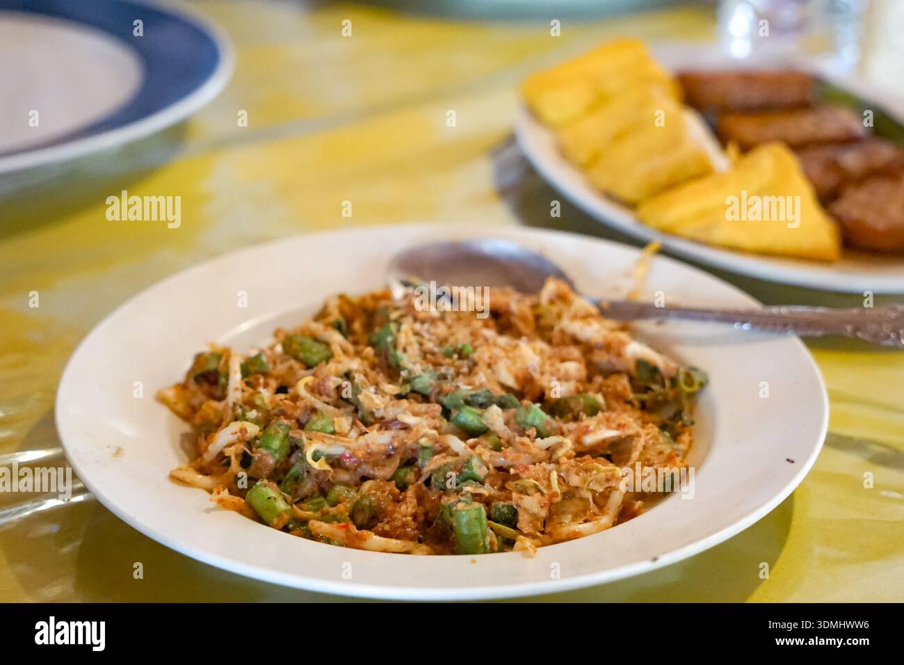 Tradizionale insalata di Lotek Sundanese con verdure al vapore, salsa di arachidi piccante, tofu e tempeh serviti su tovaglie a motivi geometrici. Foto Stock
