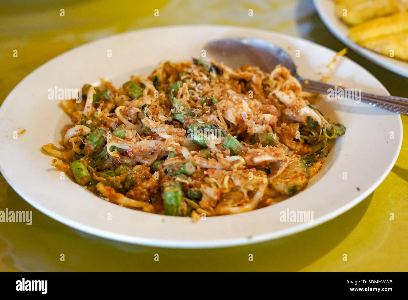 Tradizionale insalata di Lotek Sundanese con verdure al vapore, salsa di arachidi piccante, tofu e tempeh serviti su tovaglie a motivi geometrici. Foto Stock