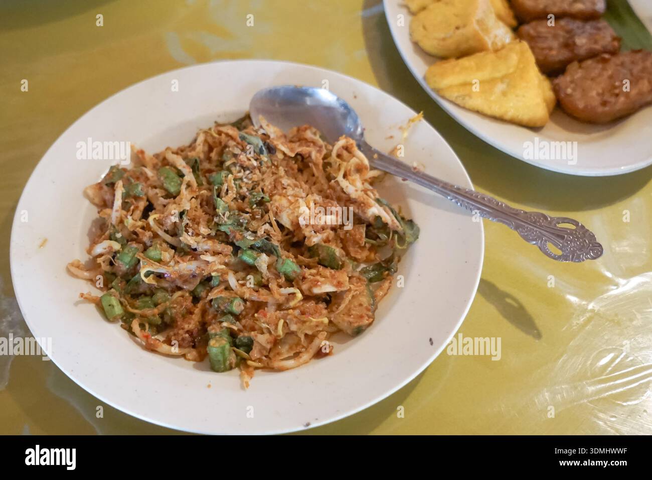 Tradizionale insalata di Lotek Sundanese con verdure al vapore, salsa di arachidi piccante, tofu e tempeh serviti su tovaglie a motivi geometrici. Foto Stock