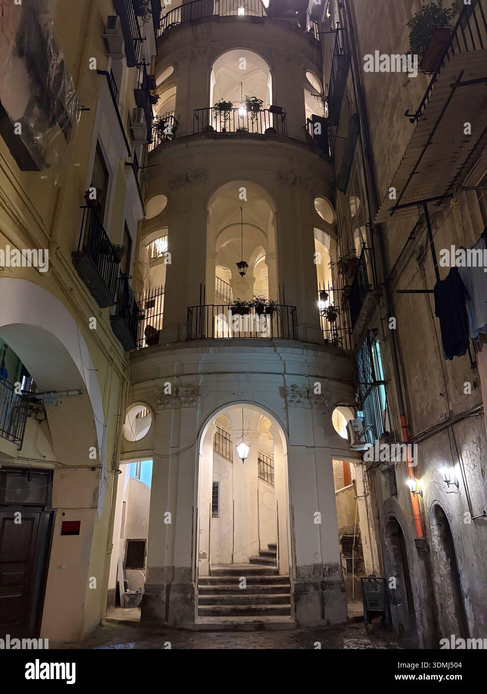Scala barocca illuminata (Scala) in un cortile interno di Napoli (Napoli). Spettacolare vista notturna dei palazzi storici con archi e manufatti Foto Stock