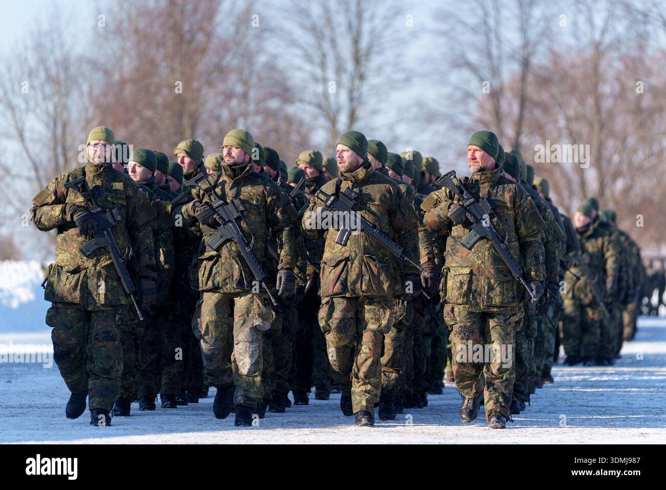 Fila di soldati tedeschi in uniforme mimetica flecktarn che marciano con fucili G36 nella neve. Foto Stock
