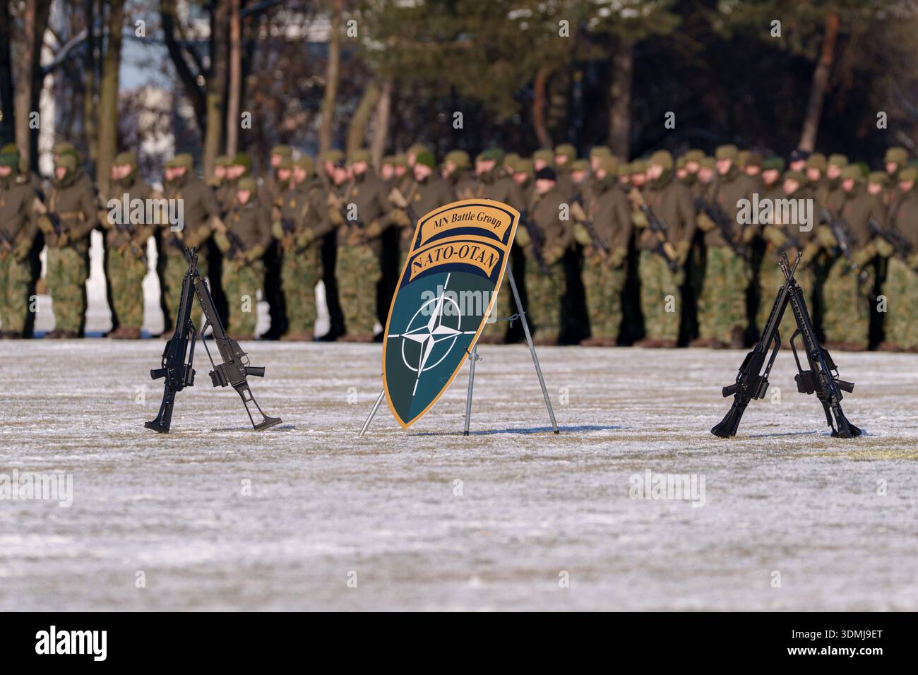 Scudo e fucili NATO Battle Group esposti sul campo con soldati sullo sfondo. Foto Stock