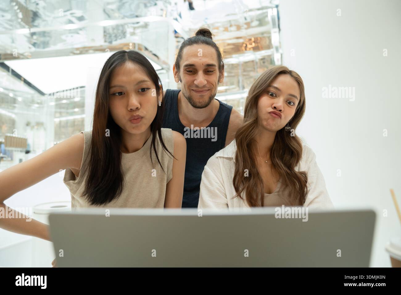 Amici eterogenei che creano volti divertenti per videochiamare un notebook Foto Stock