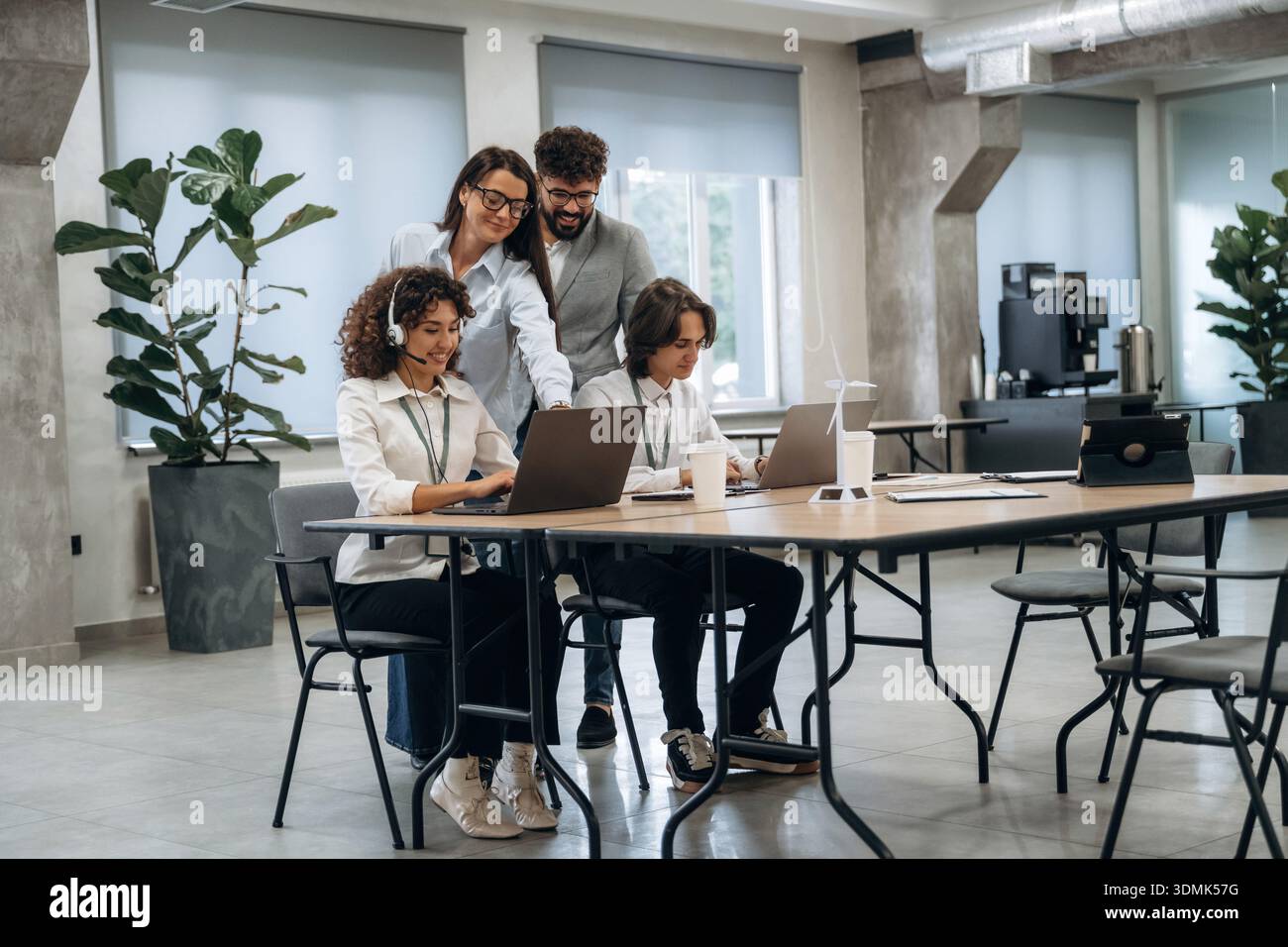 Call Center, donna con le cuffie. Un gruppo di persone lavora in ufficio insieme come un team. Foto Stock