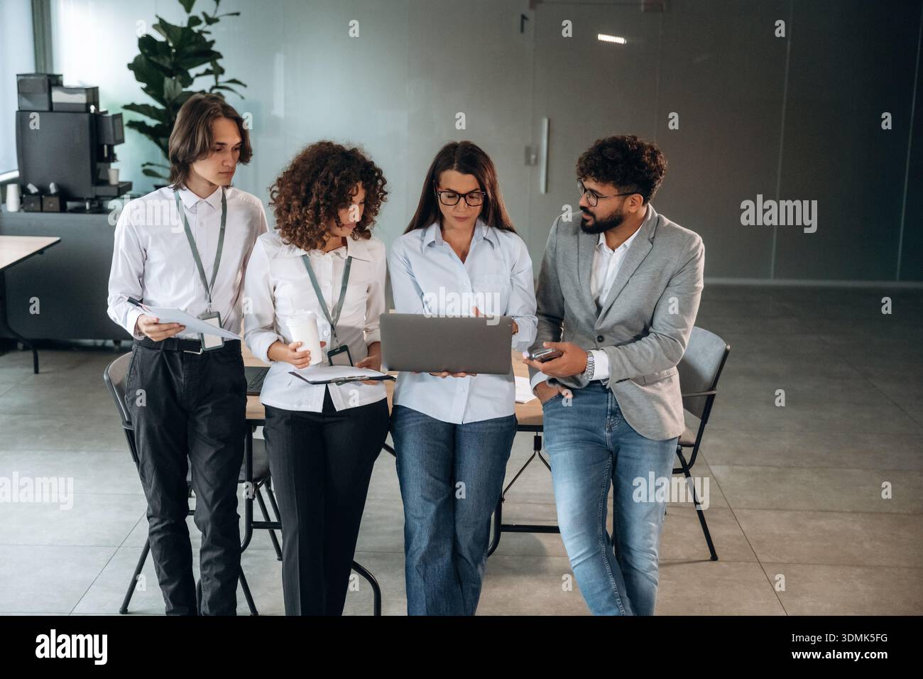 Tenere il computer portatile e stare in piedi. Un gruppo di persone lavora in ufficio insieme come un team. Foto Stock