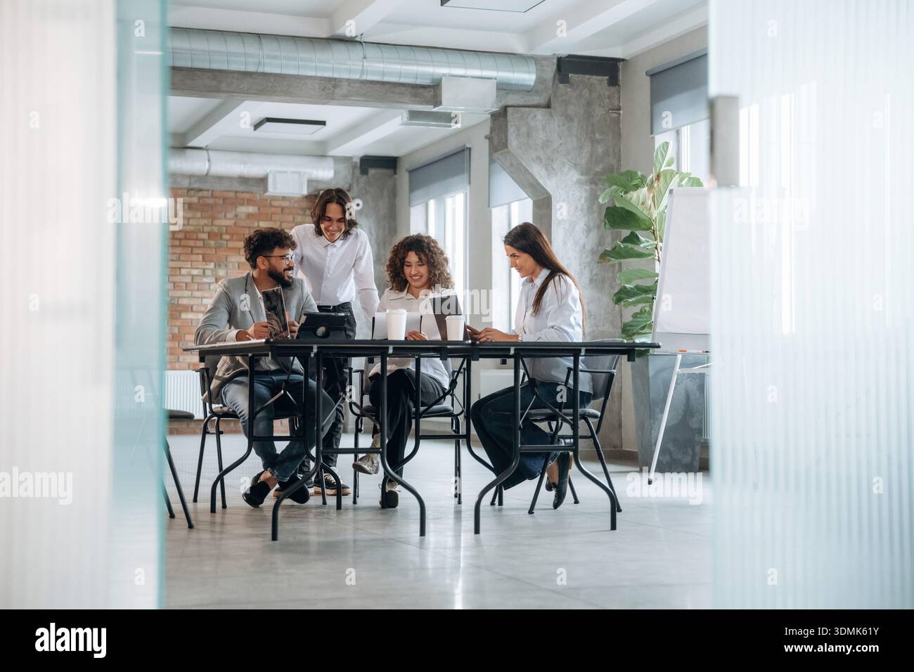 Stanza incompiuta, muro di mattoni. Un gruppo di persone lavora in ufficio insieme come un team. Foto Stock