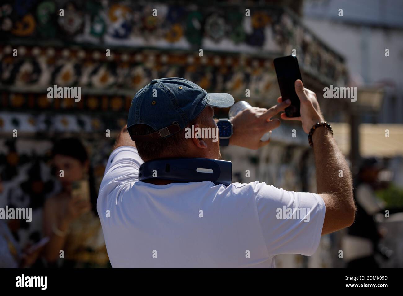 Turista maschile che scatta una foto con smartphone ed esplora il tempio tailandese, vista posteriore, Wat Arun. Foto Stock