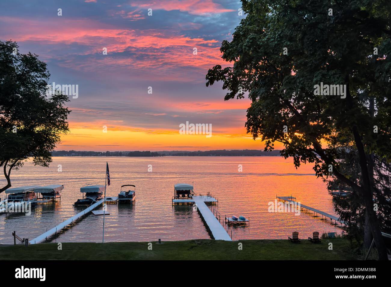 Uno spettacolare tramonto sorvola diversi moli residenziali per barche sul lago Clear in Indiana. Foto Stock