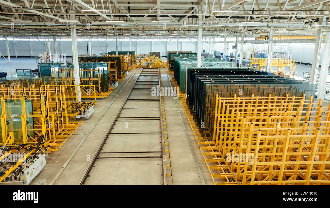 Magazzino dell'industria della produzione di finestre e vetri. Grande impianto di produzione con pannelli in vetro conservati e apparecchiature industriali. Foto Stock