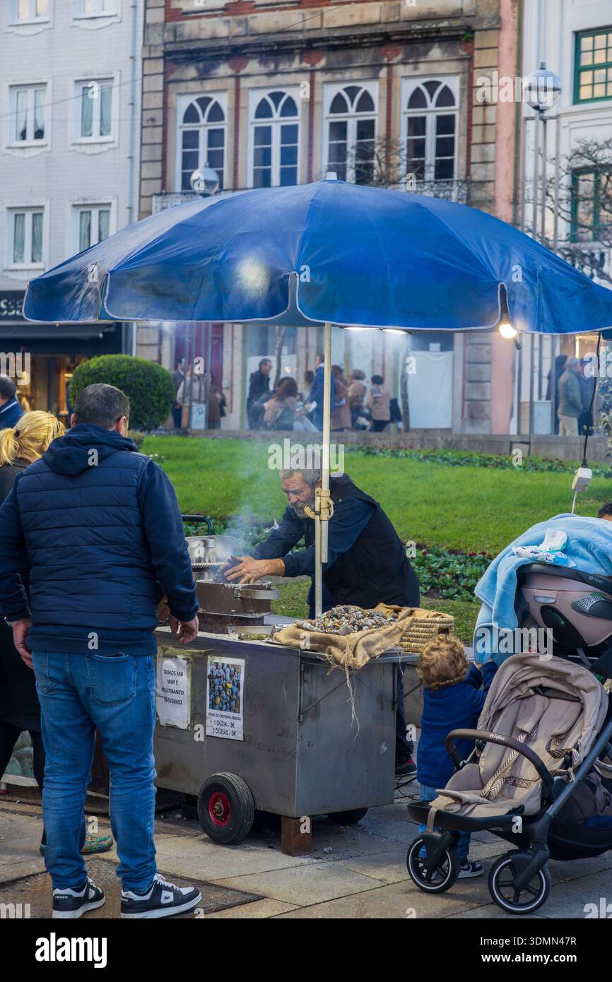 Venditore serale di castagne. Street Merchant offre castagne arrostite al tramonto. Dusk Falls mentre Street Vendor vende fragranti castagne arrostite Foto Stock