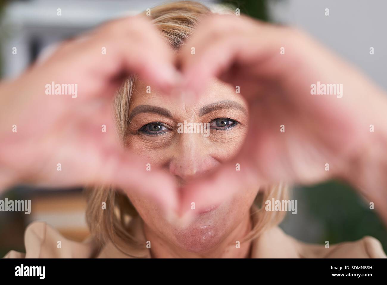Donna amichevole che inquadra una forma di cuore con le mani per un Ritratto e una connessione positivi Foto Stock