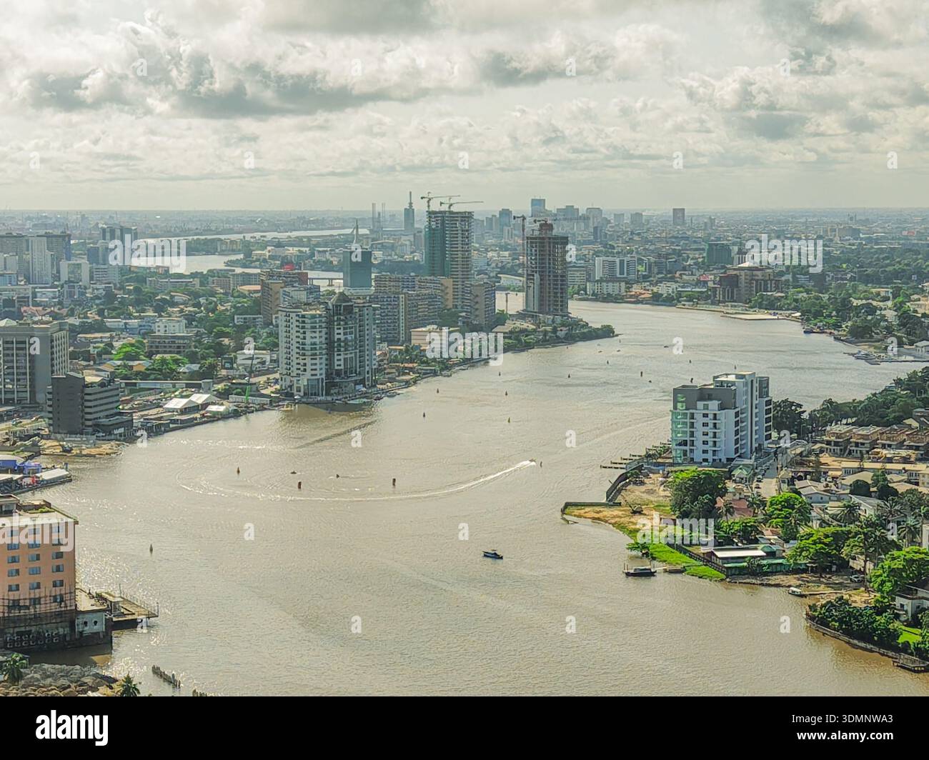 Vista aerea della Laguna di Lagos che si snoda attraverso la vibrante città, l'acqua che riflette il cielo, circondata da edifici, Lagos, Lagos, Nigeria. Foto Stock