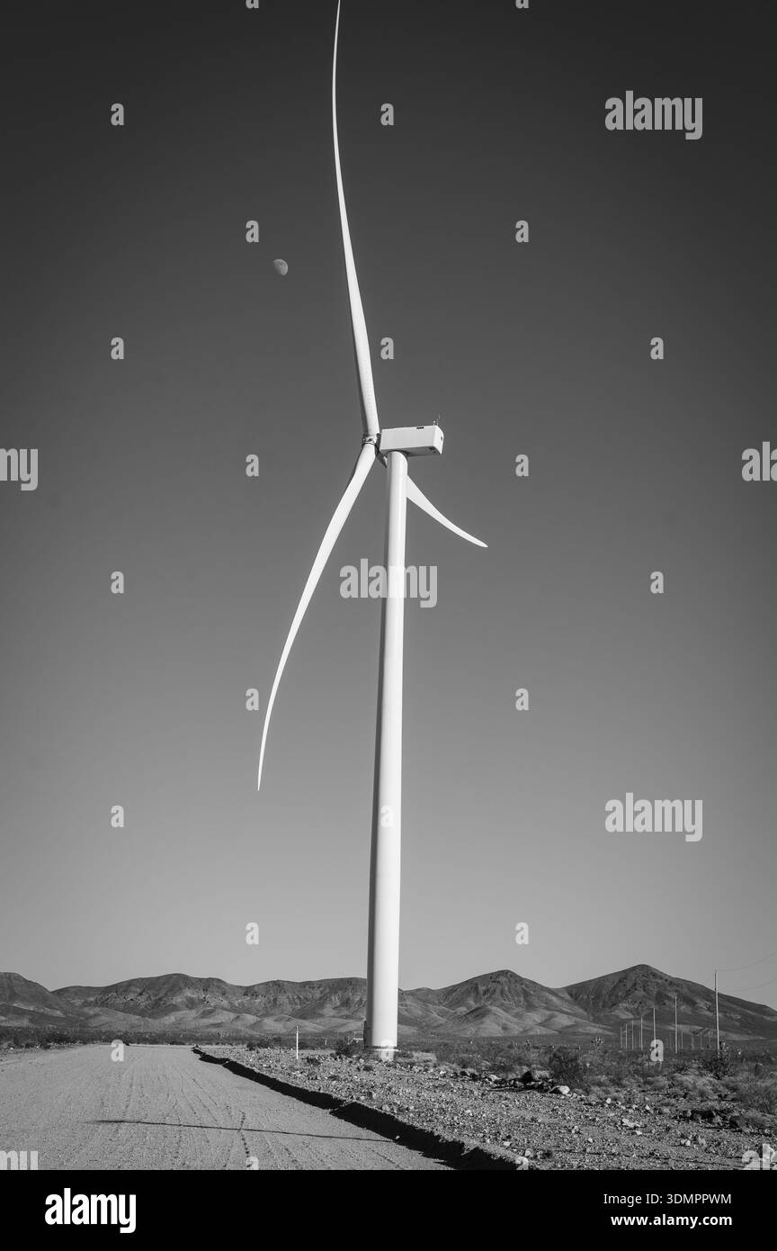 Un gigantesco mulino a vento che genera elettricità con la luna che mostra attraverso le sue pale. Un parco eolico solare tra Kingman, Arizona, e Las Vegas, Nevada. Nero A. Foto Stock