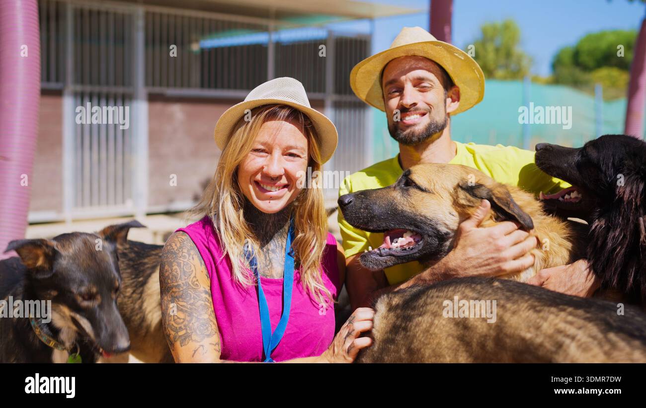 Volontari sorridenti, abbracciando cani salvati in un rifugio per animali Foto Stock