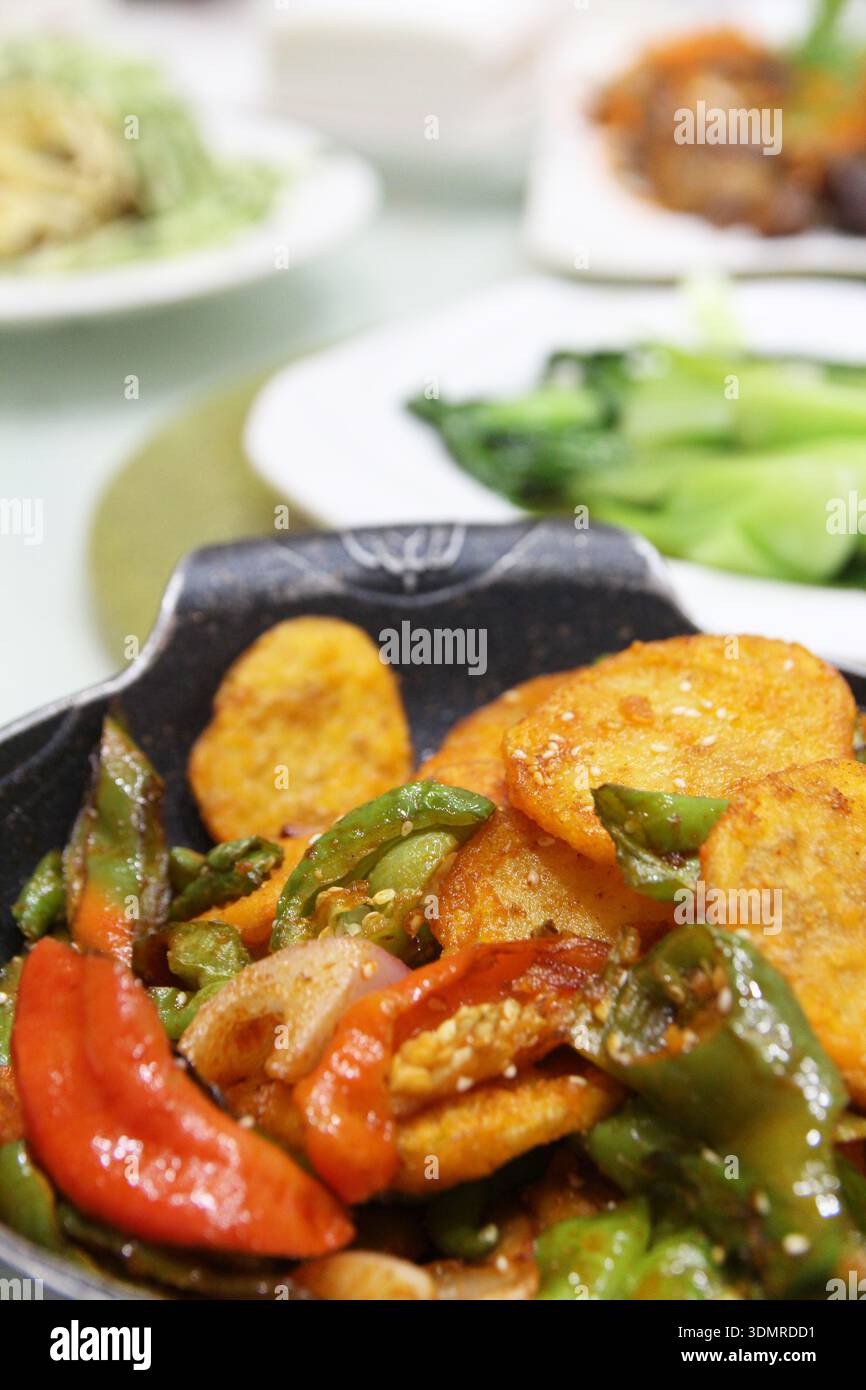Patate cinesi fritte in padella con cipolla, peperoncini rossi e verdi in un ristorante a Dunhuang, Cina Foto Stock