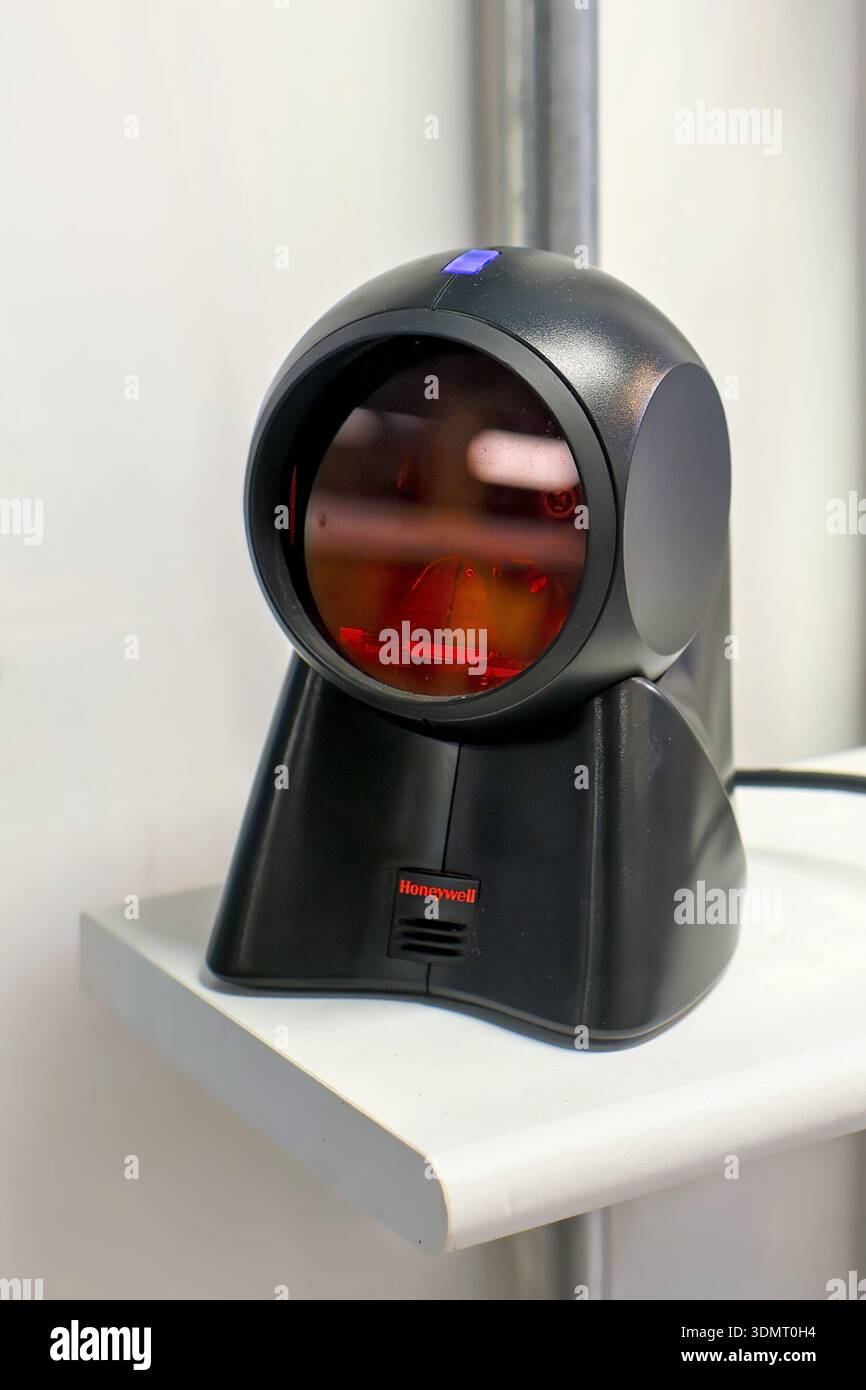 Sliema, Malta - 24 dicembre 2025: Primo piano di uno scanner laser per codici a barre Honeywell su uno scaffale bianco in un negozio locale, utilizzato per il controllo dei prezzi e l'inventario. Foto Stock