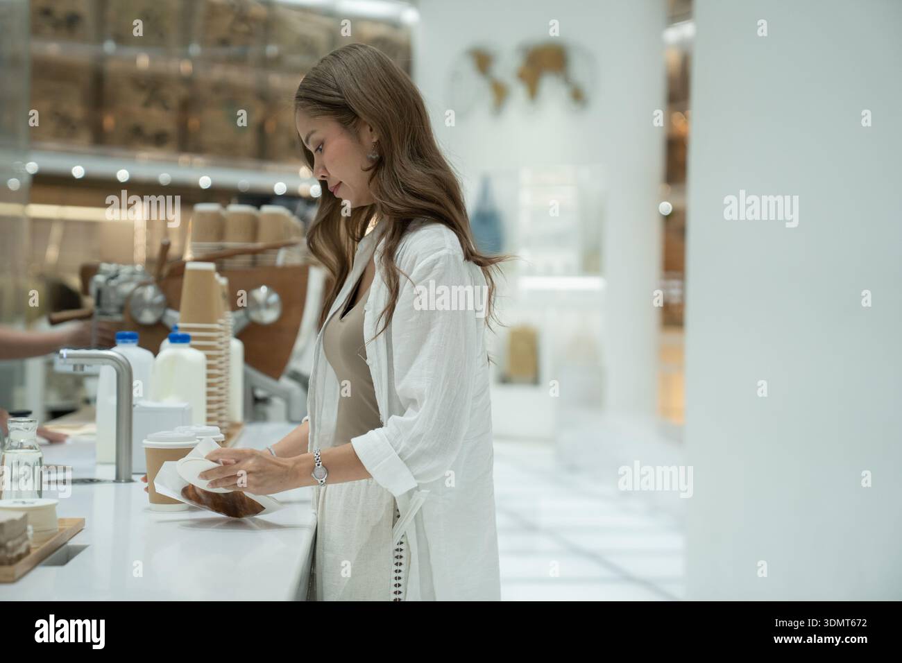 Donna che compra caffè e pasticceria in un moderno caffè minimalista Foto Stock