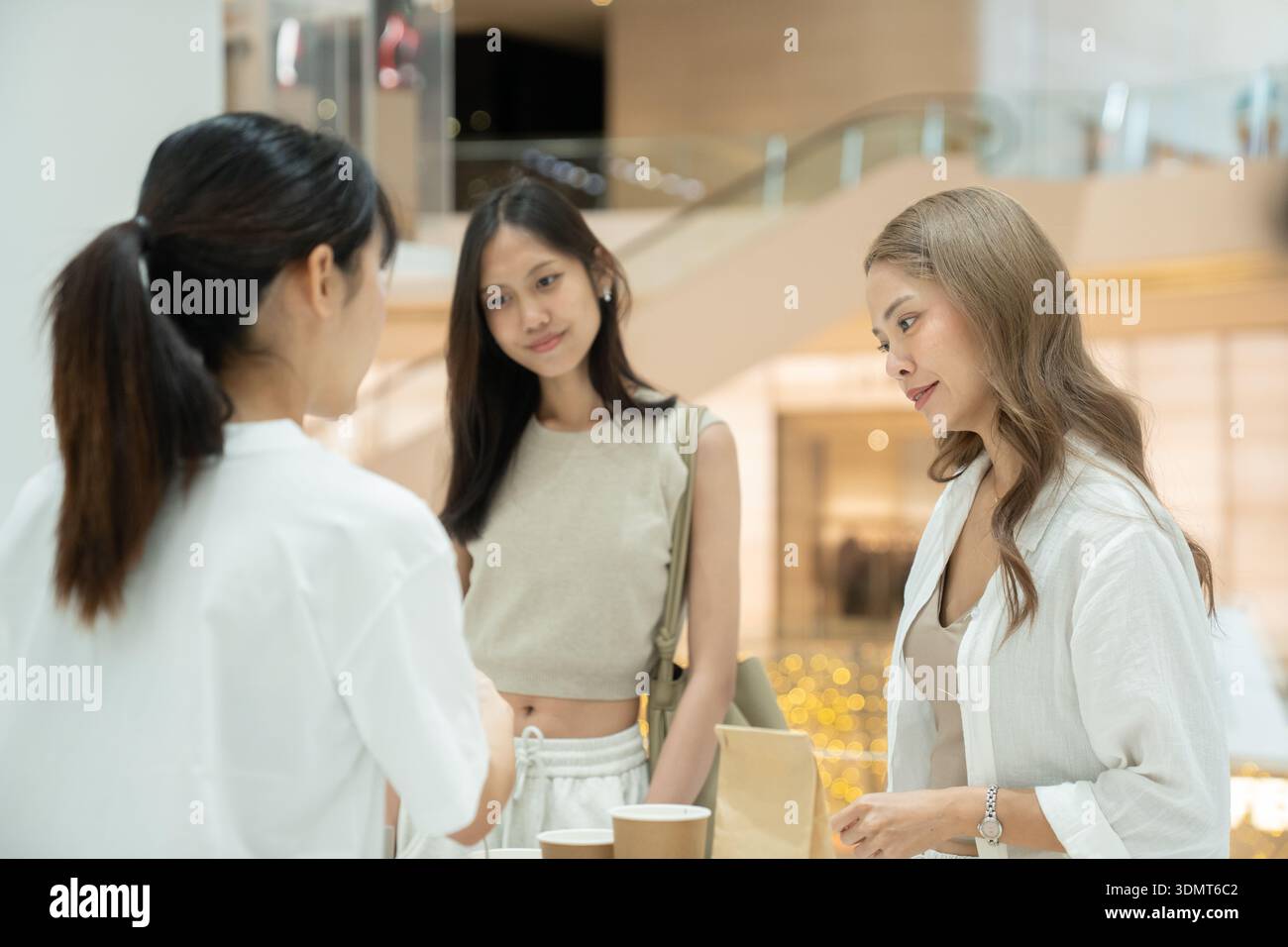 Donne che interagiscono con il venditore che riceve bevande e shopping bag Foto Stock