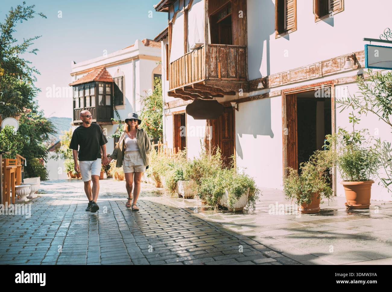 Coppia di mezza età che cammina mano nella mano lungo una stradina stretta nel centro storico della città di Kas. Viaggi romantici, relazioni d'amore, vacanze in luna di miele e.. Foto Stock
