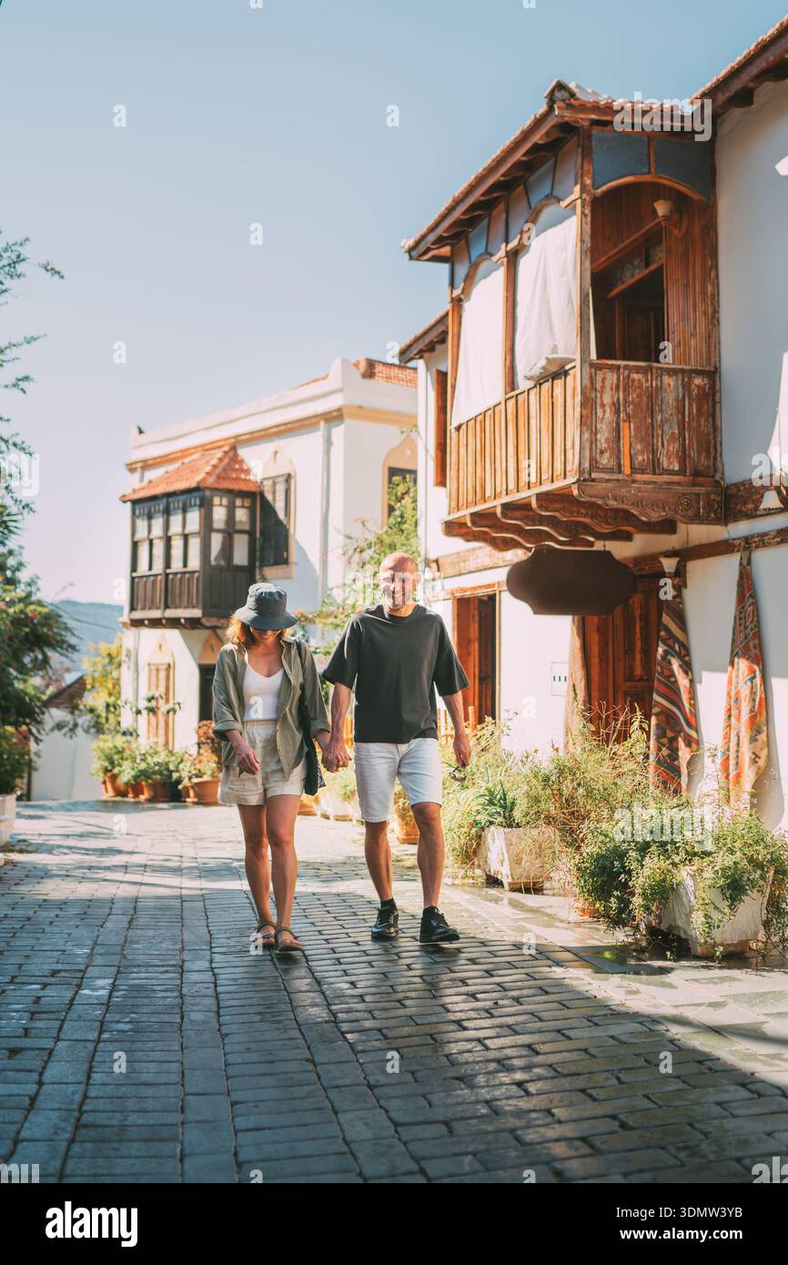 Coppia di mezza età che cammina mano nella mano lungo una stradina stretta nel centro storico della città di Kas. Viaggi romantici, relazioni d'amore, vacanze in luna di miele e.. Foto Stock