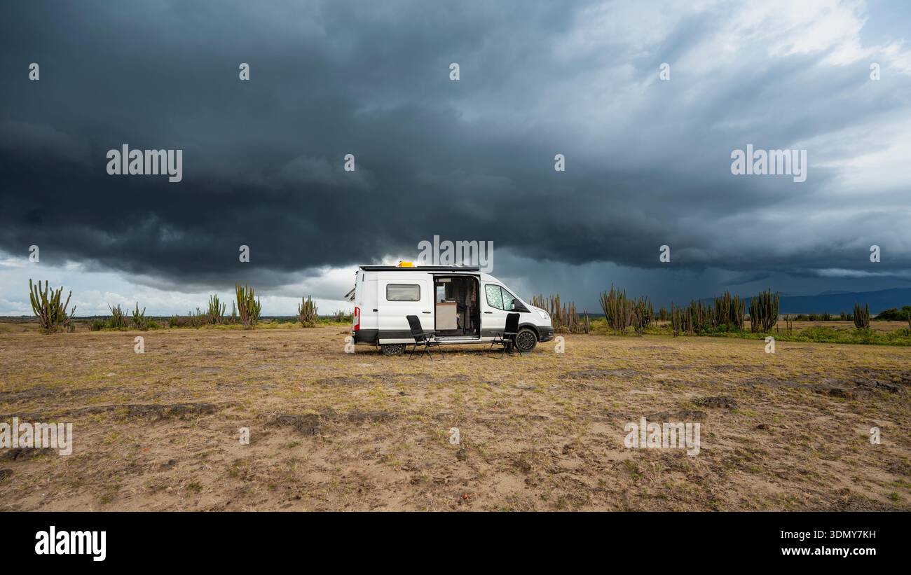 Un camper parcheggiato nel vasto deserto di Tatacoa, Colombia. Il cielo tempestoso si staglia sopra la testa, creando una scena drammatica perfetta per i nomadi digitali e. Foto Stock