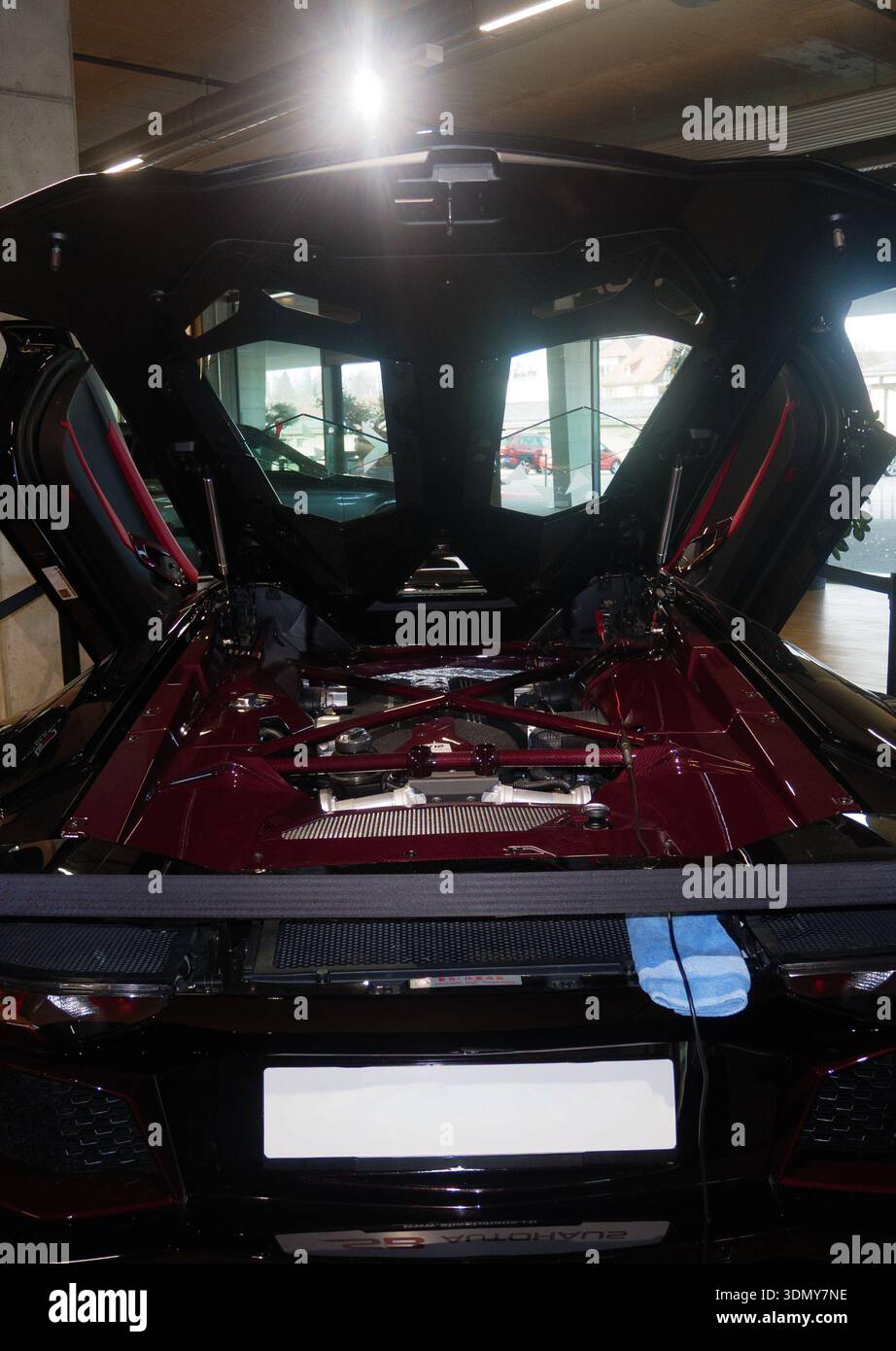 Auto sportiva di lusso con cofano aperto che rivela dettagli sui componenti del motore e caratteristiche di design moderno all'interno di uno showroom luminoso Foto Stock