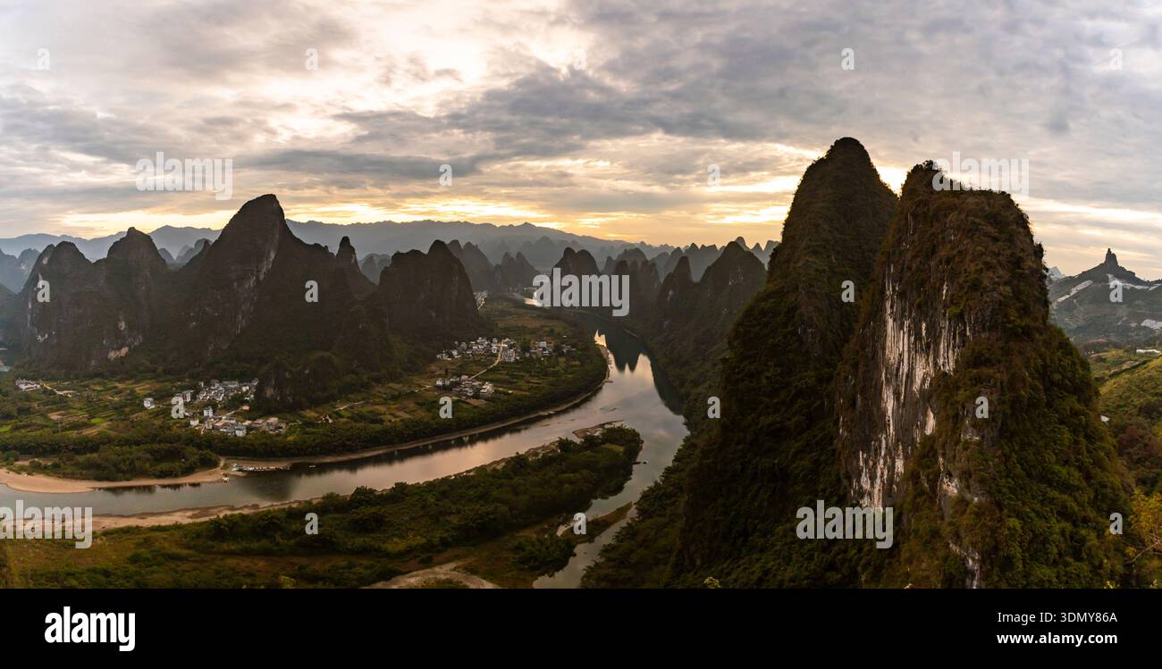 Ampia vista panoramica del fiume li che si snoda tra le montagne calcaree di Yangshuo, Guangxi. La luce soffusa del tramonto rivela picchi spettacolari, il paesaggio rurale vi Foto Stock