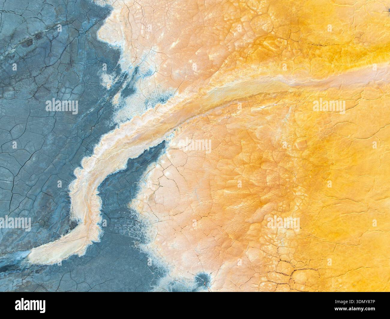 Un'immagine visivamente sorprendente del suolo contaminato che mostra un mix vibrante di sfumature blu e gialle. Le intricate trame incrinate evidenziano l'ambiente Foto Stock