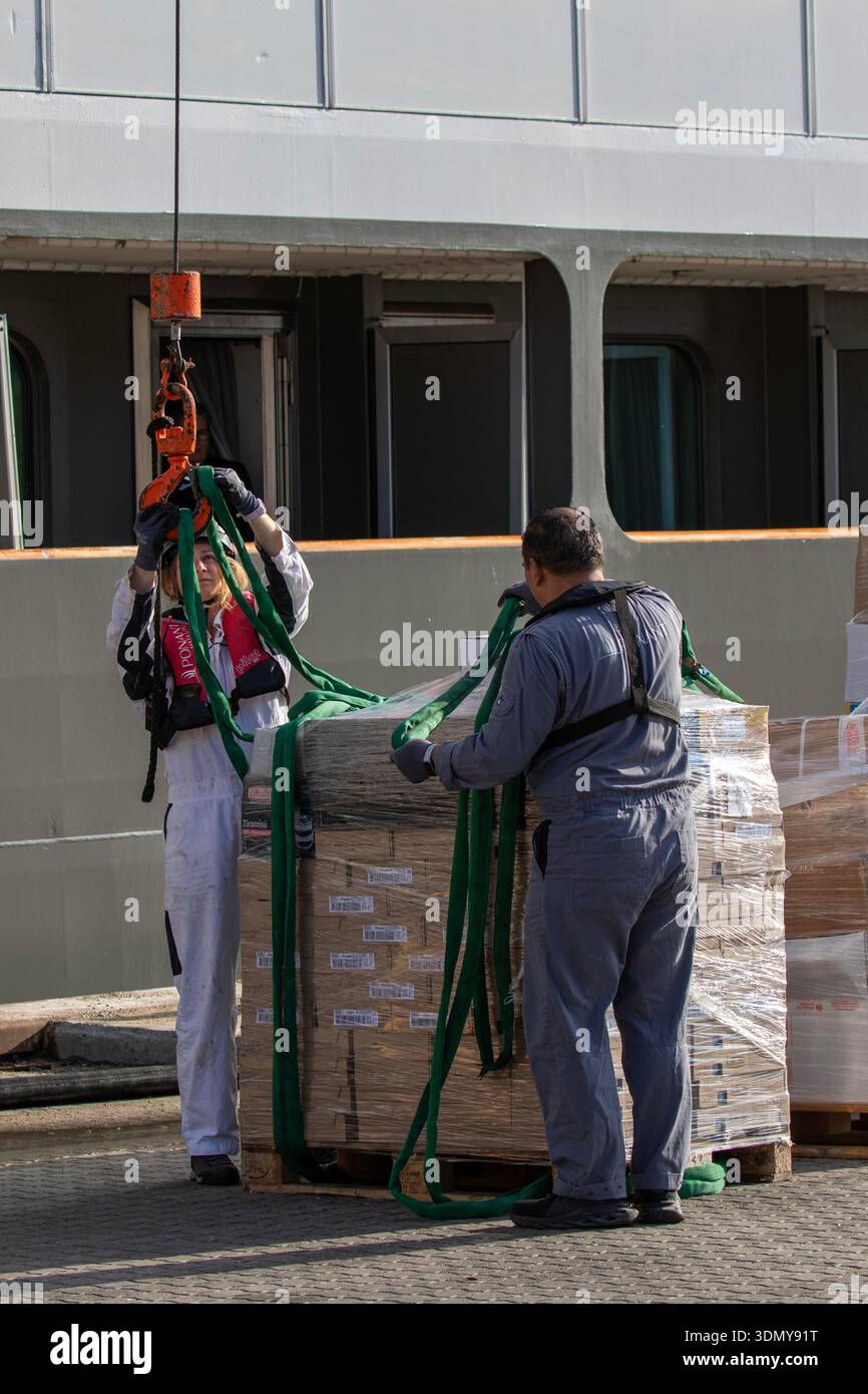Artico, Groenlandia, Sissimiut. Due lavoratori dell'equipaggio caricano rifornimenti sulla nave sul molo Foto Stock