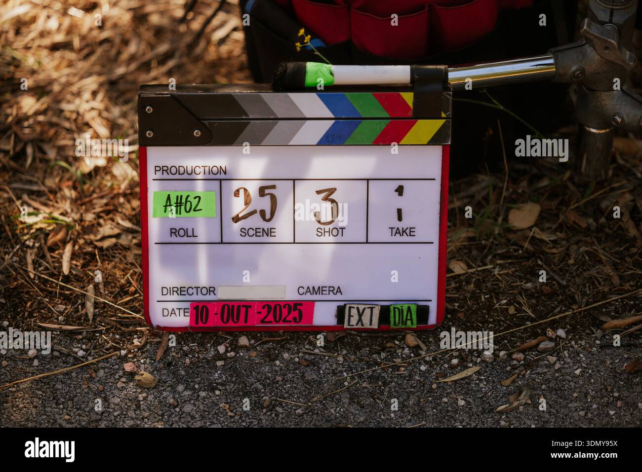 Un clapperboard su un set cinematografico all'aperto con foglie sparse per terra. Il tabellone visualizza i dettagli di produzione, come scena, ripresa e ripresa Foto Stock