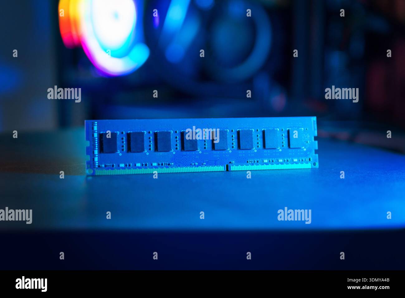 Modulo di memoria RAM singolo sulla scrivania con illuminazione blu, sfondo moderno per computer per videogame, concetto di aggiornamento hardware, prestazioni informatiche e tecnologia Foto Stock