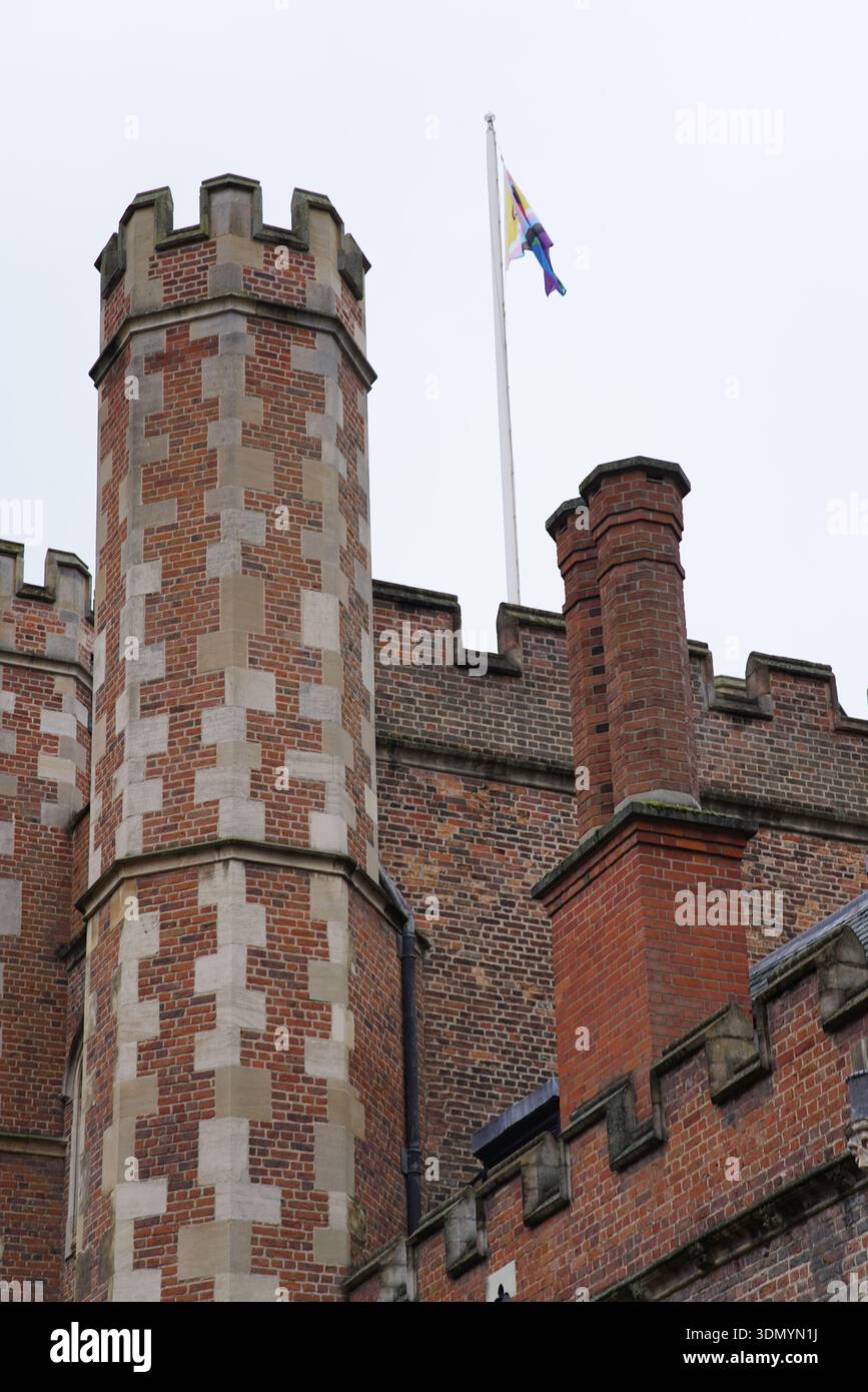 Torre in mattoni merlati e camini di uno storico college di Cambridge con bandiera che sventola in una giornata grigia coperta. Cambridge, Inghilterra Foto Stock