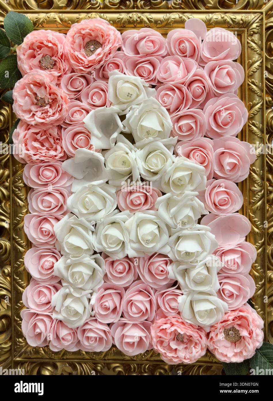 Fiori finti rosa e bianchi in una cornice color oro. Foto Stock