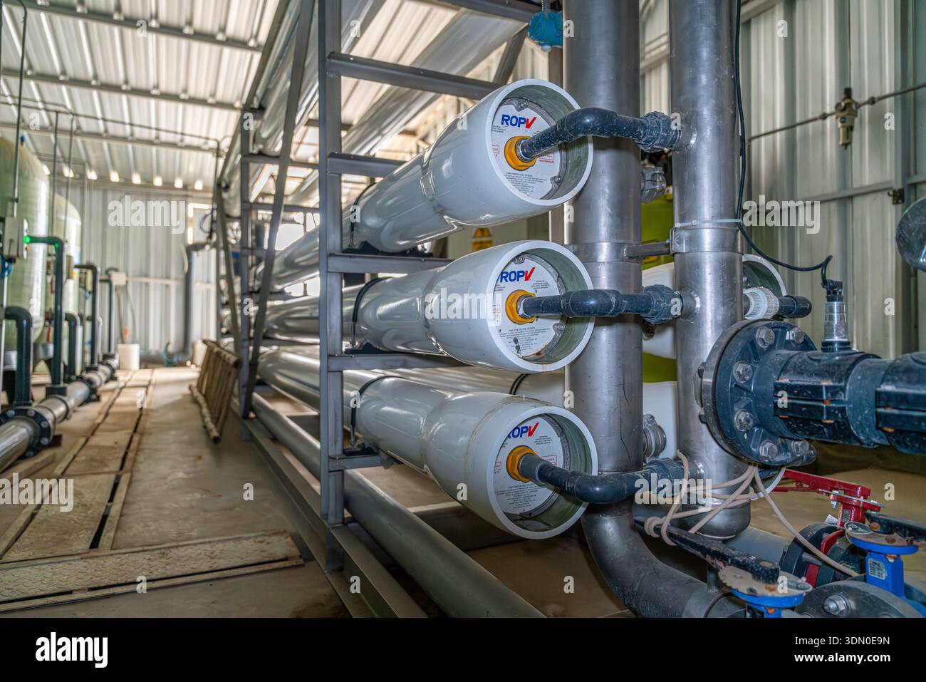 Sistema di trattamento industriale delle acque a osmosi inversa con alloggiamenti a membrana, tubi, valvole e serbatoio all'interno dell'impianto di trattamento. Foto Stock